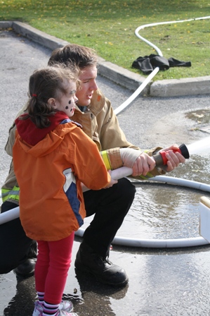 Little girl being shown how a fire hose works